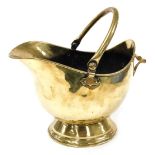 A late 19th/early 20thC brass helmet shaped coal scuttle, on a domed foot, with a swing handle, 43cm