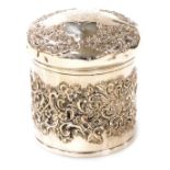 A Victorian silver dressing table box, of cylindrical form embossed profusely with flowers, leaves a