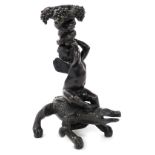 An early 20thC bronze Bacchanalian figural candlestick, in the form of a Bacchanalian cherub seated