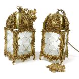 A pair of heavy brass and glass hall lanterns, embossed with flowers and foliate scrolls, the panels