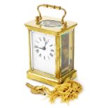 A brass cased carriage clock, with white enamel dial and Roman numerals, within a plain brass case,