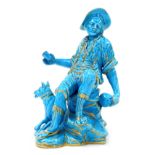 A late 19thC Continental turquoise porcelain figure group, modelled as a boy seated on a rock with a