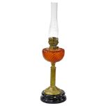 A Victorian brass column oil lamp, with amber tinted glass reservoir and a ceramic base, 71cm high i