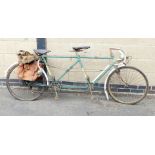 A vintage Reynolds tandem bicycle, in green trim, with leather seats and various canvas saddlebags.