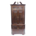 A George III mahogany standing corner cupboard, with swan neck pediment, dentil moulded cornice,