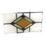 A stained glass panel, with a diamond orange green and red centre, 28cm high, 53cm wide. (AF)