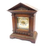 A late 19thC German oak cased mantel clock, the brass square dial with foliate spandrels, circular s