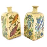 A pair of Persian Iznik Qajar pottery bottles, each on a cream glazed ground, depicting birds and f