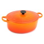 A Le Creuset orange ovenware casserole dish and cover, 30cm wide.