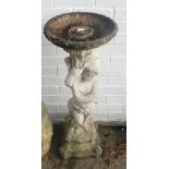 A reconstituted stone bird bath, formed as a child tugging cloth, on a shaped base, 92cm high.