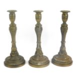 Three Louis XVI brass candlesticks, each with heavy swag and scroll decoration, weighing 1537g, 1436