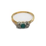 An 18ct gold emerald and diamond dress ring, set with square cut emerald, flanked by two tiny diamon
