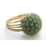 An emerald cluster ring, formed as a ball with oval cut emeralds in claw setting, on a five splayed