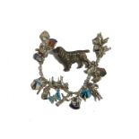 A silver dog brooch, with plain pin back, 5cm wide, and a charm bracelet with many white metal and o