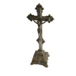An early 20thC silver plated crucifix, heavily decorated with raised scrolls, on a hammered ground,