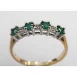 An emerald and diamond half hoop dress ring, set with four round brilliant cut emeralds in claw sett