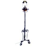 An early 20thC wrought iron and copper adjustable floor lamp, with oil reservoir, on triform base, c