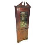 A mahogany standing corner cabinet, with a broken pediment above a single glazed door, the base with