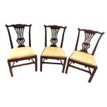 A set of three George III mahogany dining chairs, each with an elaborately leaf carved back, pierce