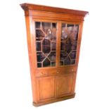 A pine standing corner cabinet, with a moulded cornice, above two astragal glazed doors enclosing sh