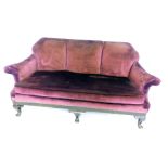 A 20thC sofa, upholstered in maroon velvet, with loose cushions, on short cabriole legs and pad feet