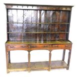 A George III oak dresser, with panelled back having two shelves, iron hanging hooks to the upper pla