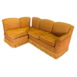 An 'L' shaped four seater corner settee, in brown upholstery and with tasselled fringe, on block fee