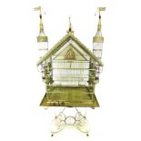 A large Continental cream and red painted bird cage, on stand, modelled in the form of a palace with