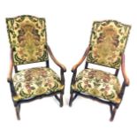 A pair of late 19thC Continental walnut open armchairs, each with a padded back and seat, upholstere