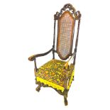 A Continental walnut open armchair, the tall back with a carved crest, above a caned panel, on turne