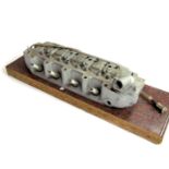 A vintage car cylinder head, No 18L, UG840338, on plinth, the unit 43cm wide, the base 60cm wide.