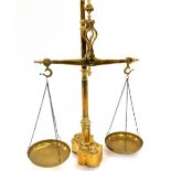 A set of Portuguese brass balance scales, with brass pans, raised on shaped base inset with eight gr