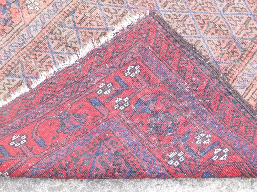 A Caucasian red ground runner, with a central floral geometric rectangular field, within repeating f - Image 3 of 3