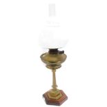 An early 20thC Williams and Bach brass oil lamp, raised on a hexagonal mahogany and satinwood banded