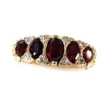 A 9ct gold and garnet five stone ring, set with pairs of diamonds at intervals, in a high claw setti
