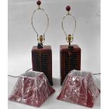 A pair of Chinese faux red lacquer wooden table lamps, of rectangular section, inset to the side pan