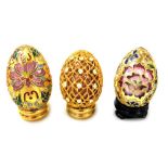 Two Chinese cloisonne enamel eggs on stands, and an egg with gilt metal and floral enamelled overlay