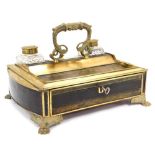 A Victorian brass and leather bound desk stand, with brass carrying handle, having two cut glass ink