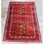A Turkoman red ground rug, decorated with three central panels of floral and foliate motifs, within