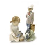 A Nao porcelain figure of a boy, modelled standing with a puppy looking up at him, and a further Nao