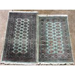 A pair of Bokhara turquoise ground rugs, decorated with a central rectangular panel with twenty-two