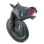A late 19thC plaster horse's head, painted in black, raised on a oval ebonised mount, 63cm high, 65c