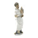 A Lladro porcelain figure of a doctor, modelled standing, holding a newborn baby.