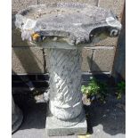 A composition bird bath, the top of shaped form, on a grape and vine cast column, on a square base,