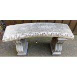A composition garden bench, the top of arched form, raised on two scroll cast end supports, 53cm hig
