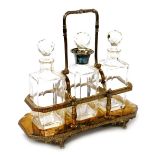 A late Victorian silver plated tantalus, with three cut glass decanters, the central decanter with a