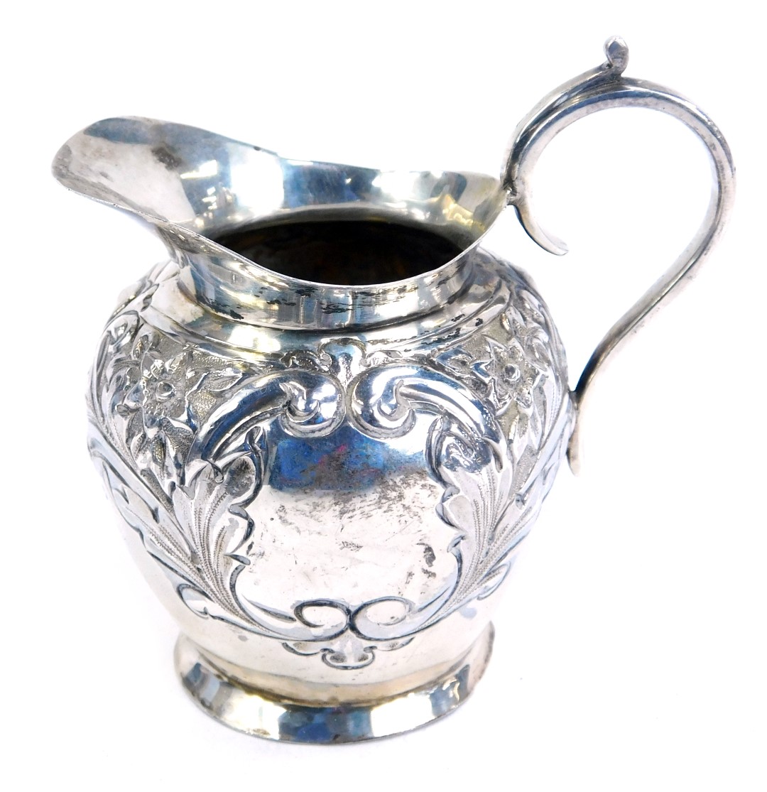 An Edwardian silver cream jug, of tapered ovoid form, with repousse decoration of flowering foliates