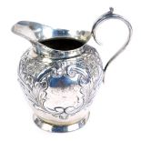 An Edwardian silver cream jug, of tapered ovoid form, with repousse decoration of flowering foliates