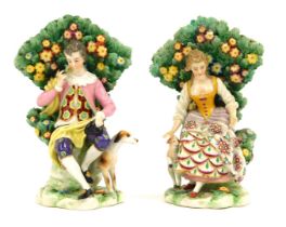 A pair of Continental Derby style porcelain figure groups, of lady and gentleman seated on perch wit