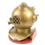 A reproduction brass diver's helmet, with cross over grill, on a treated teak base, 48cm high.